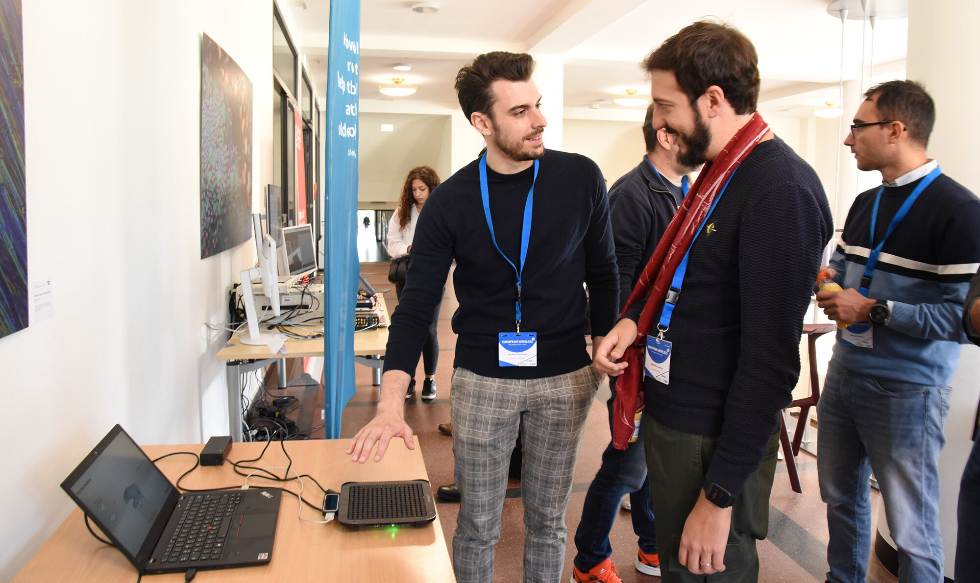 Conference participants discussing research and demonstrations at the European Wireless networking event.